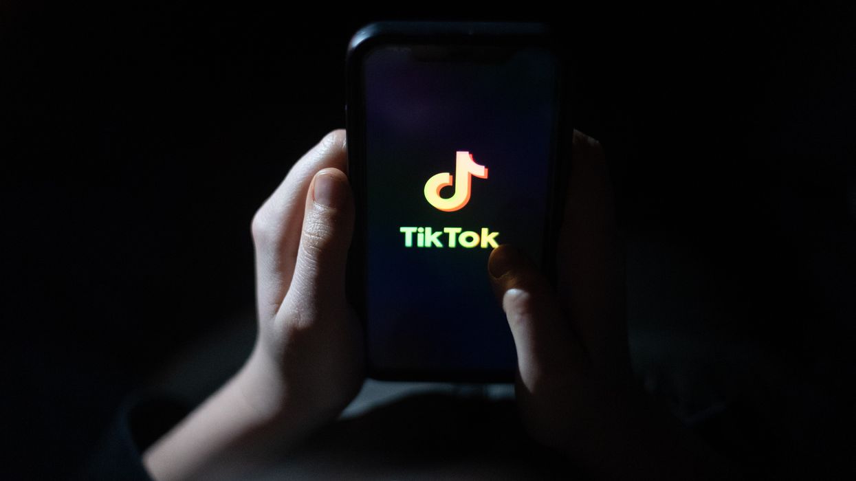 a pair of hands hold a smartphone with the tiktok logo on-screen