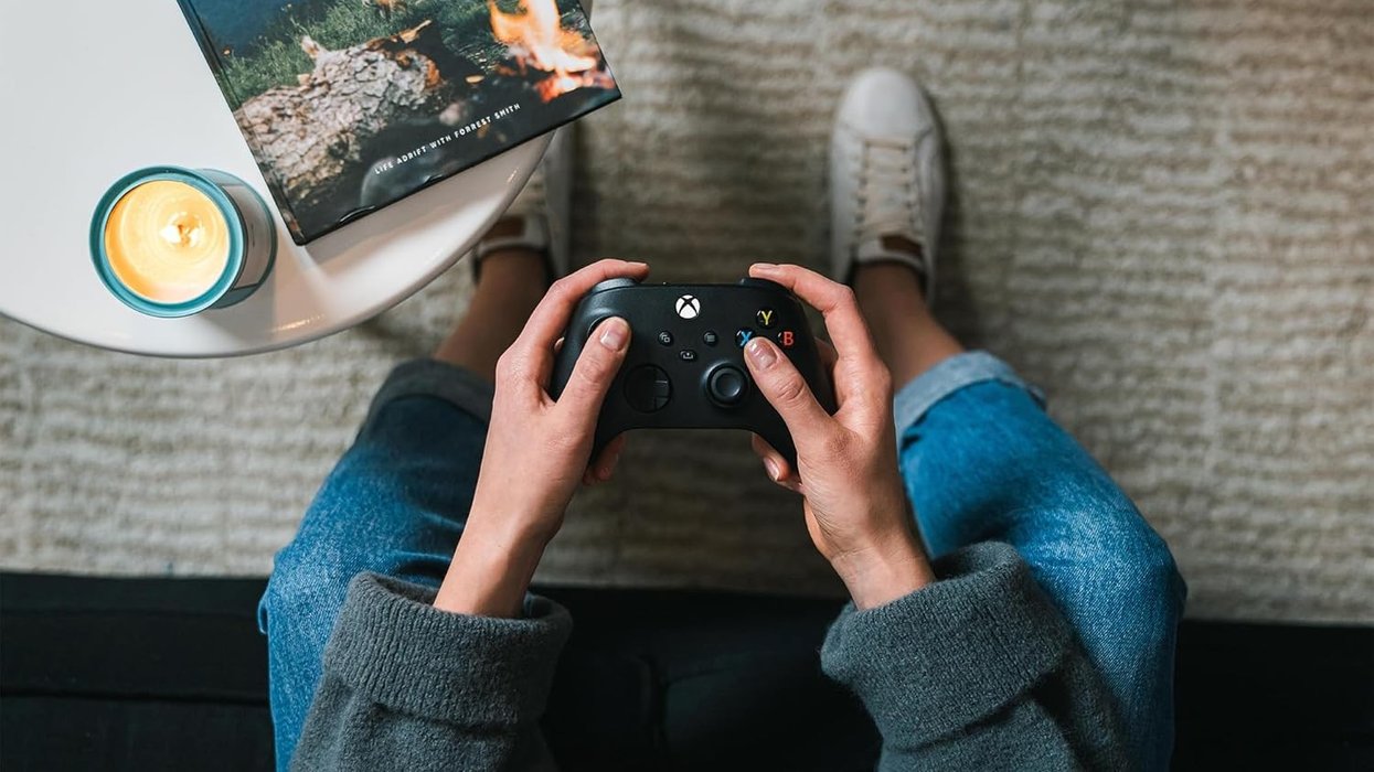 a pair of hands hold an xbox wireless controller on the sofa playing games on fire tv stick
