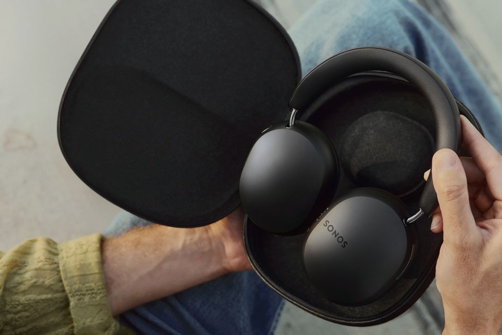 a pair of hands hold the sonos ace headphones in their carry case