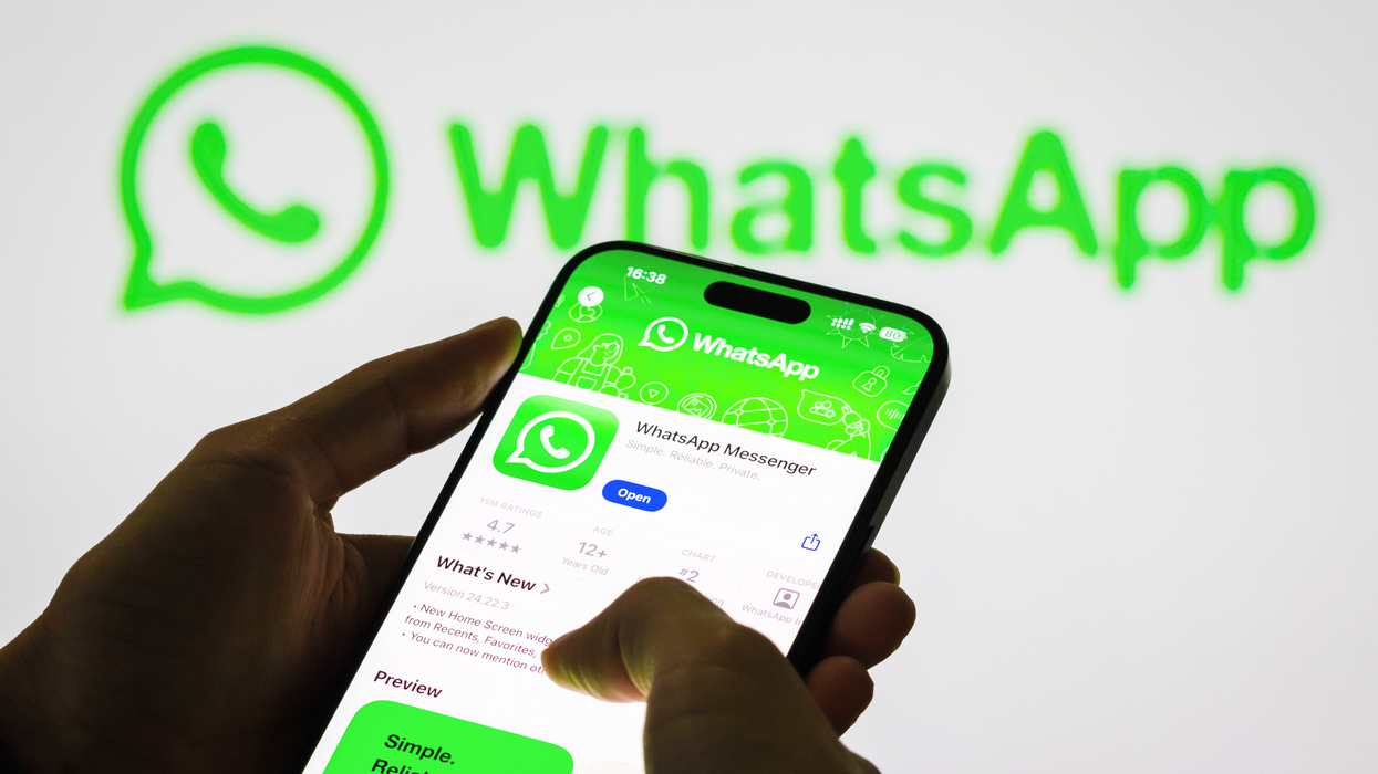 a pair of hands holds a newer iPhone model with Face ID looking at the Apple Store listing for WhatsApp