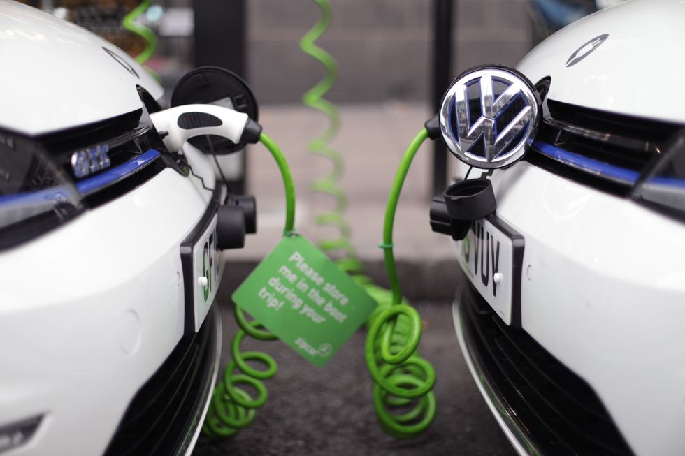 A pair of Zipcar club car-sharing Volkswagen Golf GTE plug-in petrol-electric hybrid cars being recharged on a street in central London