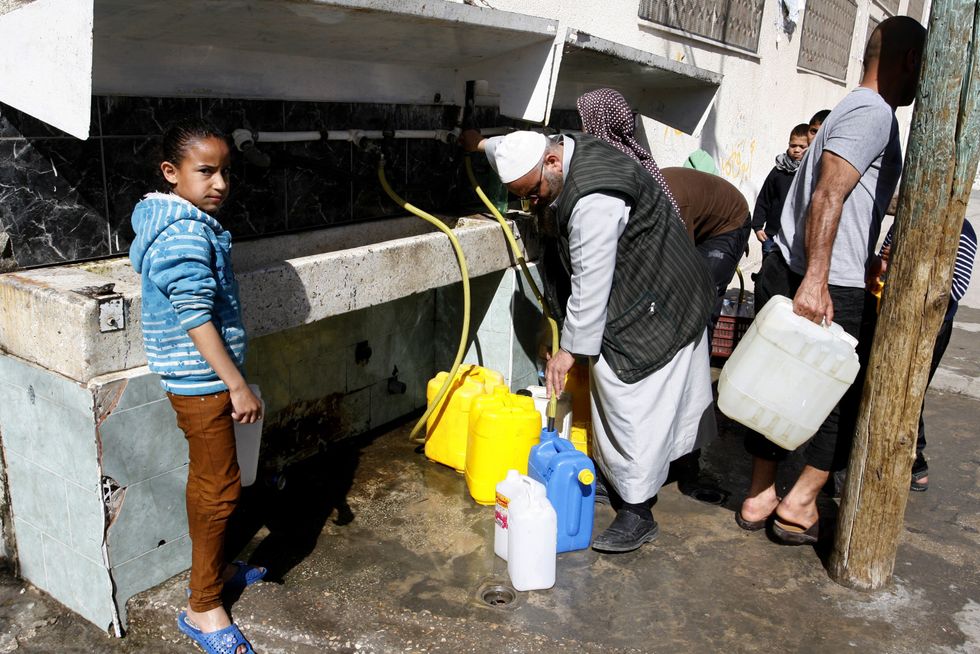 A Palestinian fills water from pipes provided by the United Nations Relief and Works Agency