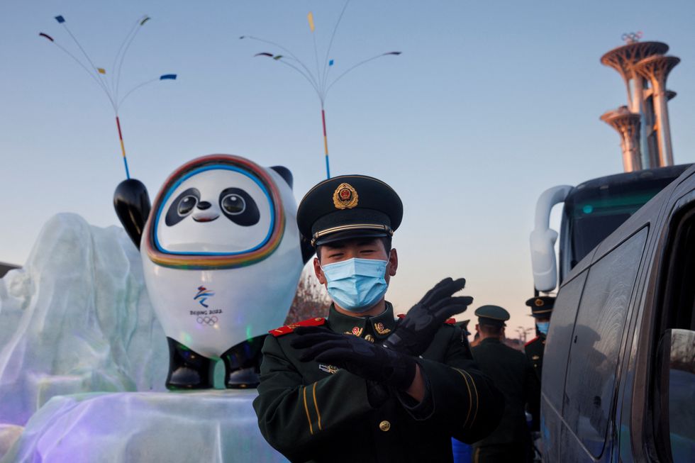 A paramilitary police officer gestures at the photographer in front of the mascot of the Beijing 2022 Winter Olympics in Beijing, China, January 15, 2022. REUTERS/Thomas Peter
