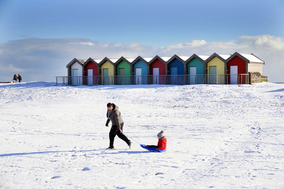 A parent and child enjoy the snow on Blyth beach