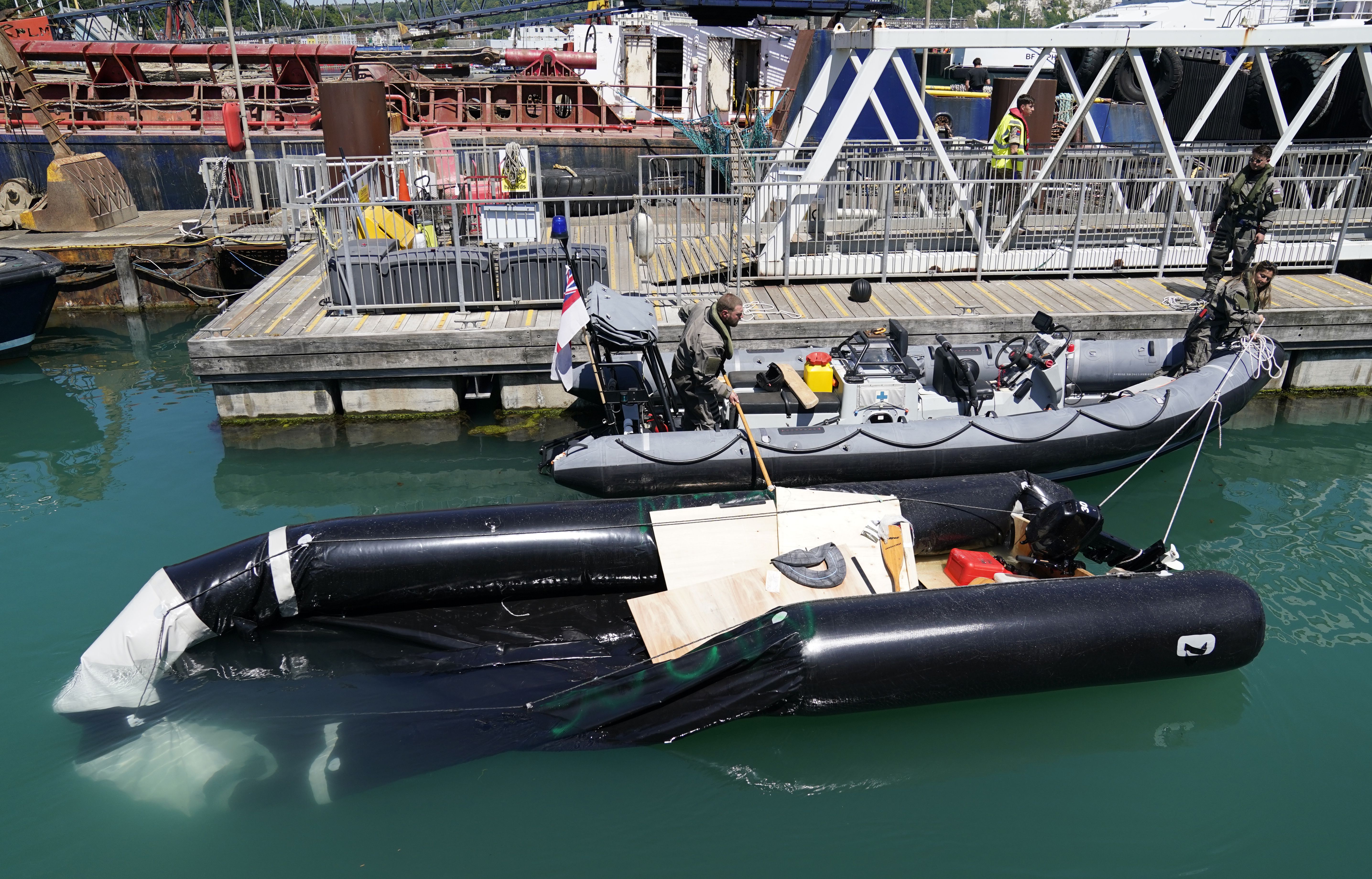 A partially submerged inflatable boat is brought into the marina after a group of people thought to be migrants are brought in to Dover, Kent, by Border Force, following a small boat incident in the Channel. Picture date: Tuesday June 14, 2022.