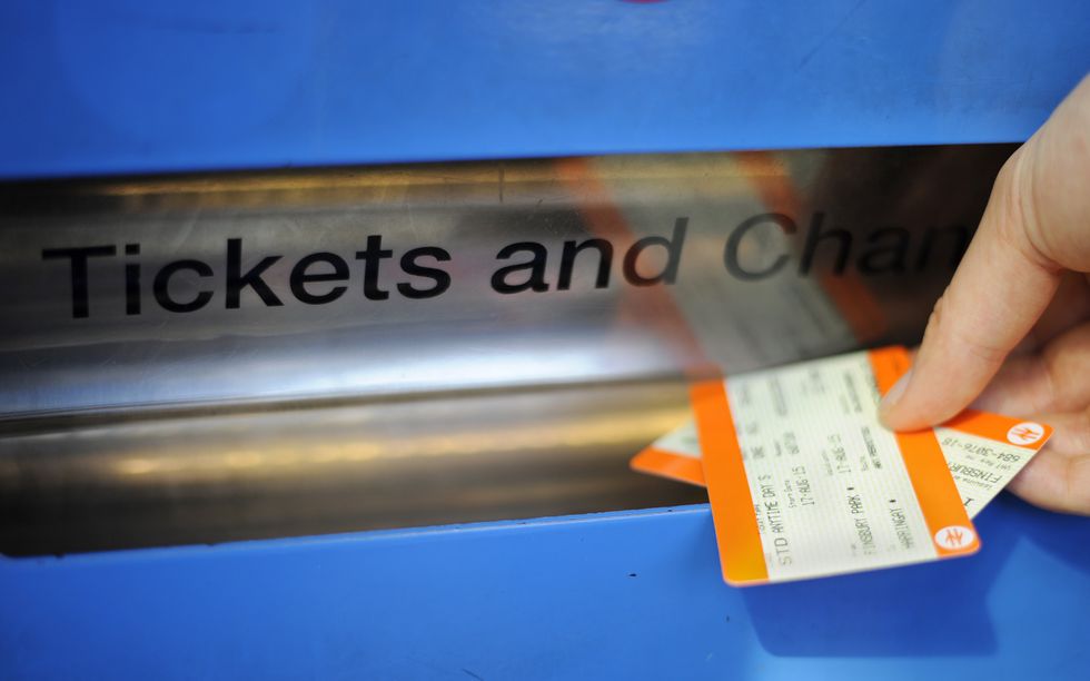 A passenger collects tickets from a ticket machine