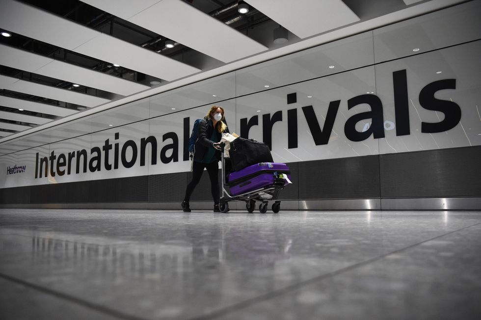 A passenger pushing luggage through the Arrival Hall of Terminal 5 at London's Heathrow Airport.