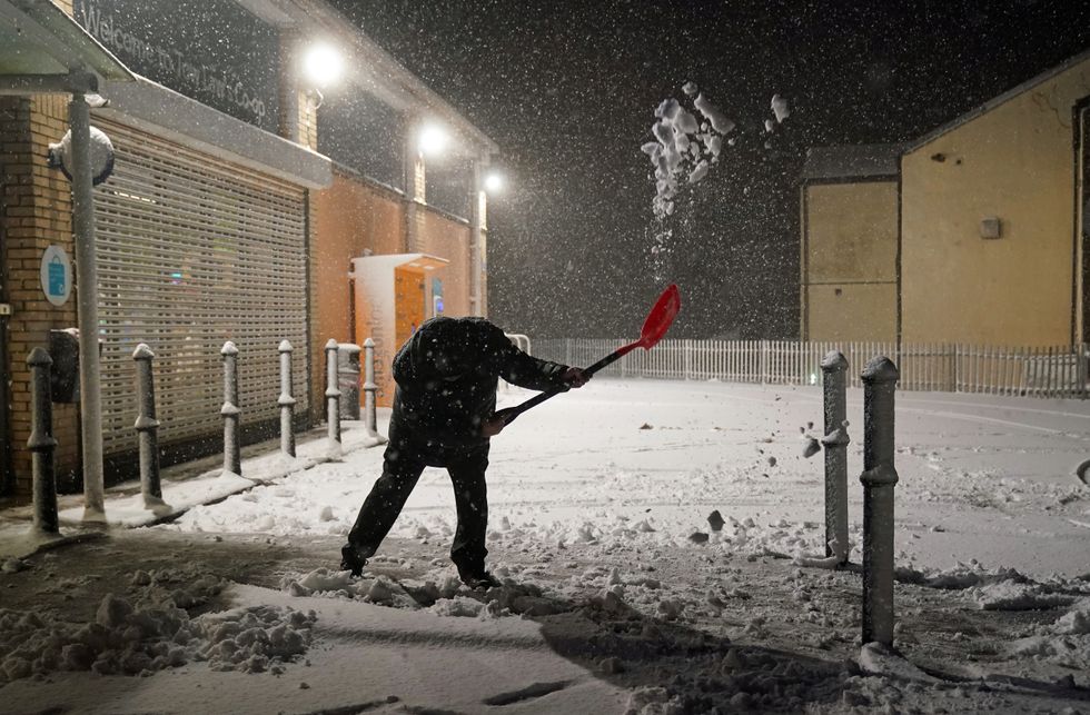 A person clears snow in Tow Law, County Durham, as Storm Eunice sweeps across the UK after hitting the south coast earlier on Friday. With attractions closing, travel disruption and a major incident declared in some areas, people have been urged to stay indoors. Picture date: Friday February 18, 2022.