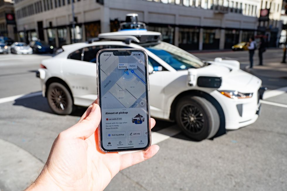 A person hailing a Waymo self-driving vehicle