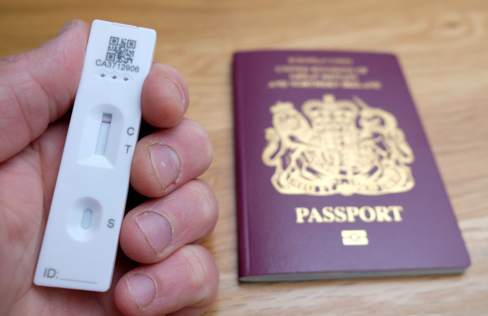 A person holding a negative lateral flow Covid-19 test in front of a passport for the United Kingdom of Great Britain and Northern Ireland.
