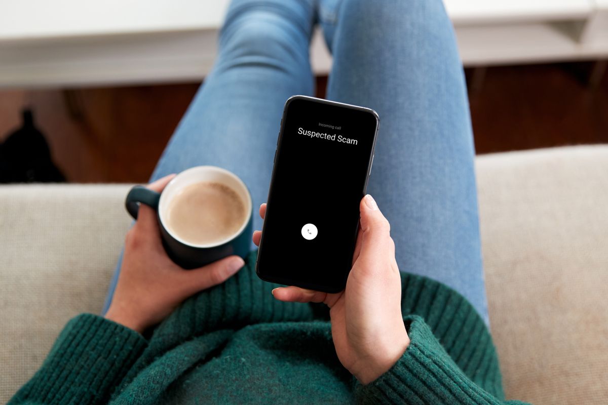 a person holding a phone with a suspected scam label on-screen