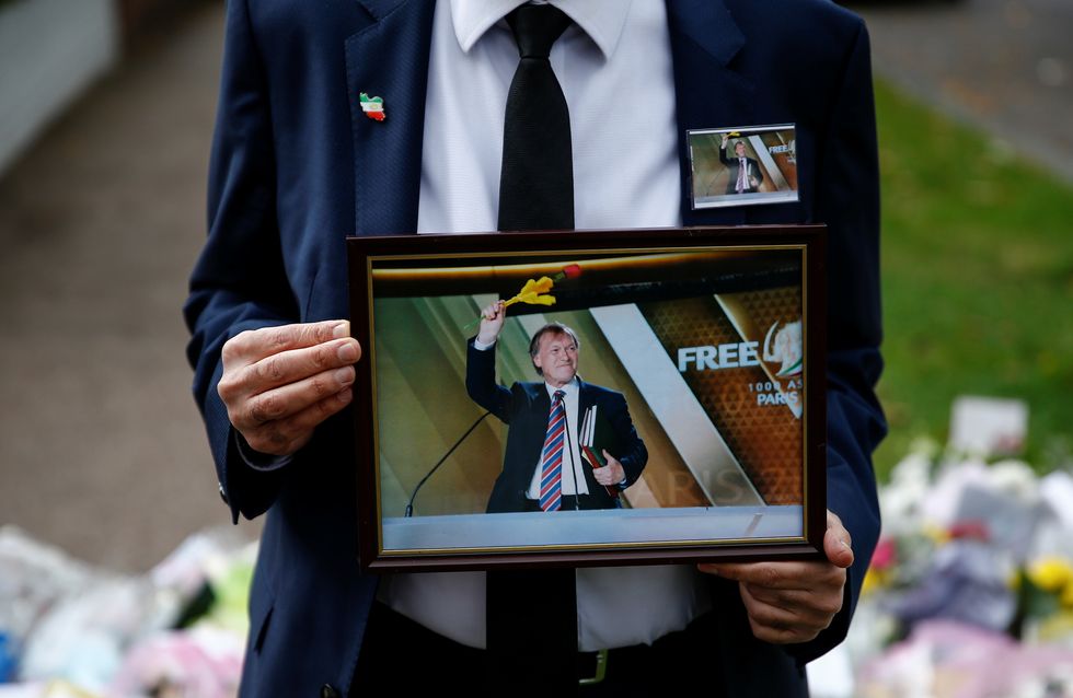A person holds a photograph of British MP David Amess, who was stabbed to death during a meeting with constituents, near the Belfairs Methodist Church, in Leigh-on-Sea