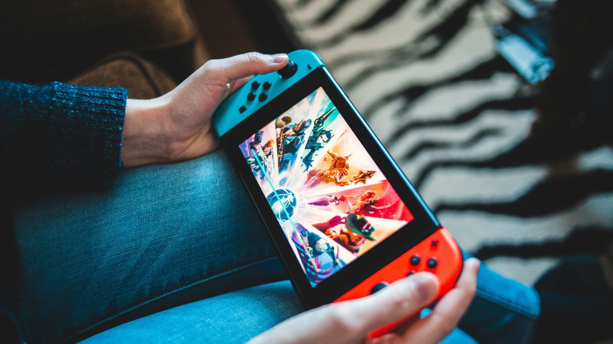 a person holds the original nintendo switch in thier hands with blue and red joy-con controllers