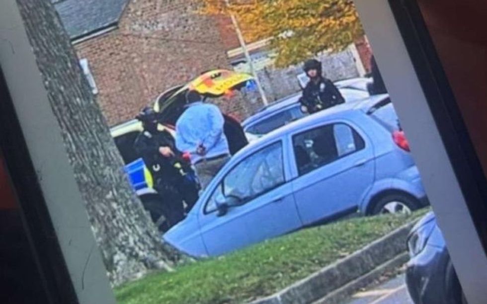 A person in handcuffs being led away by police