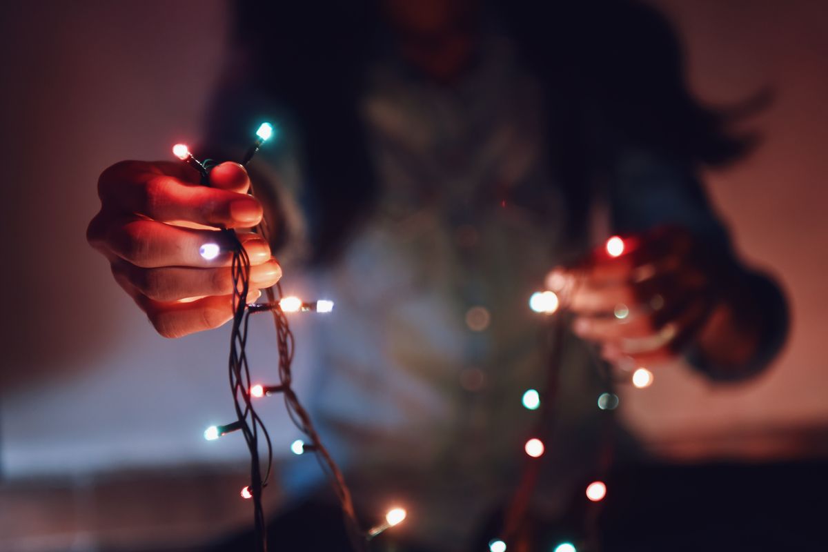a person is pictured holding out a string of fairy lights that are glowing in multiple colours