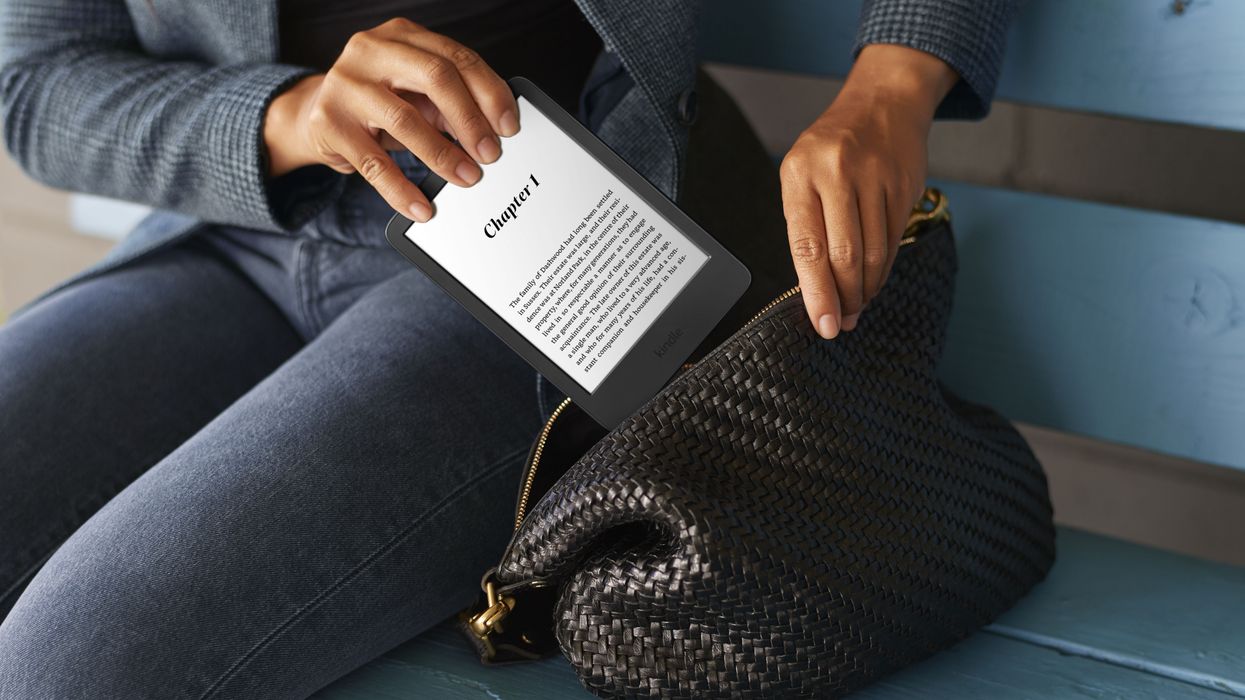a person is pictured putting an amazon kindle paperwhite with the screen illuminated into a bag