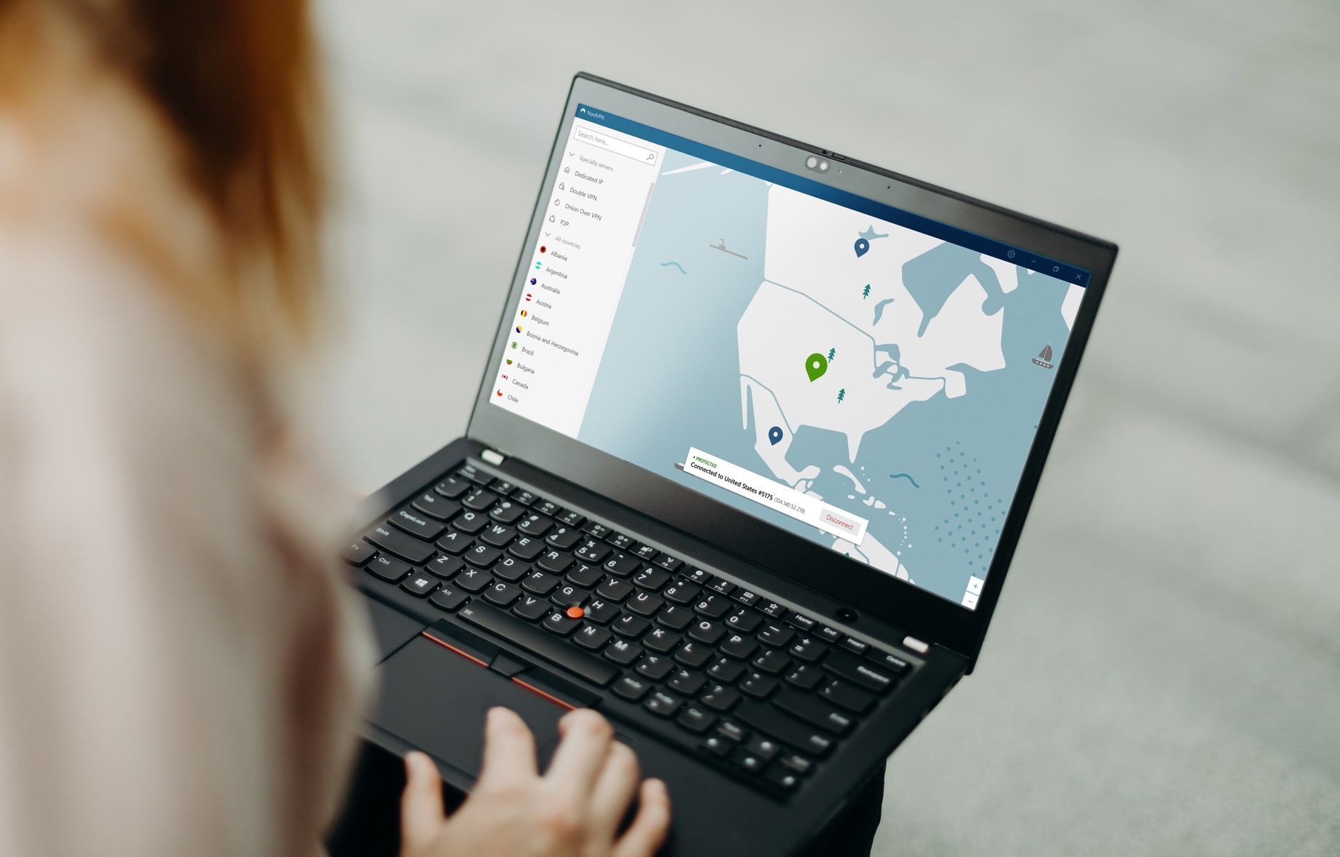 a person sits with a windows laptop and connects to a vpn server location in the usa