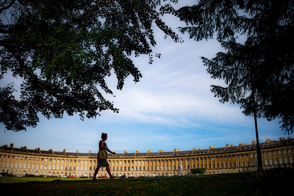 A person stays in the shade as they walks past the Royal Crescent in the city of Bath