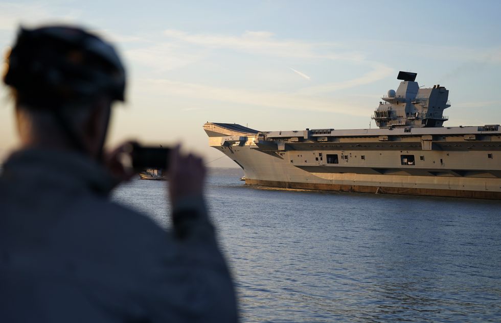 A person takes a photograph as the Royal Navy aircraft carrier HMS Prince of Wales leaves Portsmouth Harbour as it sets sail for exercises. For the next year will serve as the Nato command ship, after the Royal Navy took charge of Nato's fast reaction maritime task force formed to tackle major incidents around the world. Picture date: Wednesday January 12, 2022.