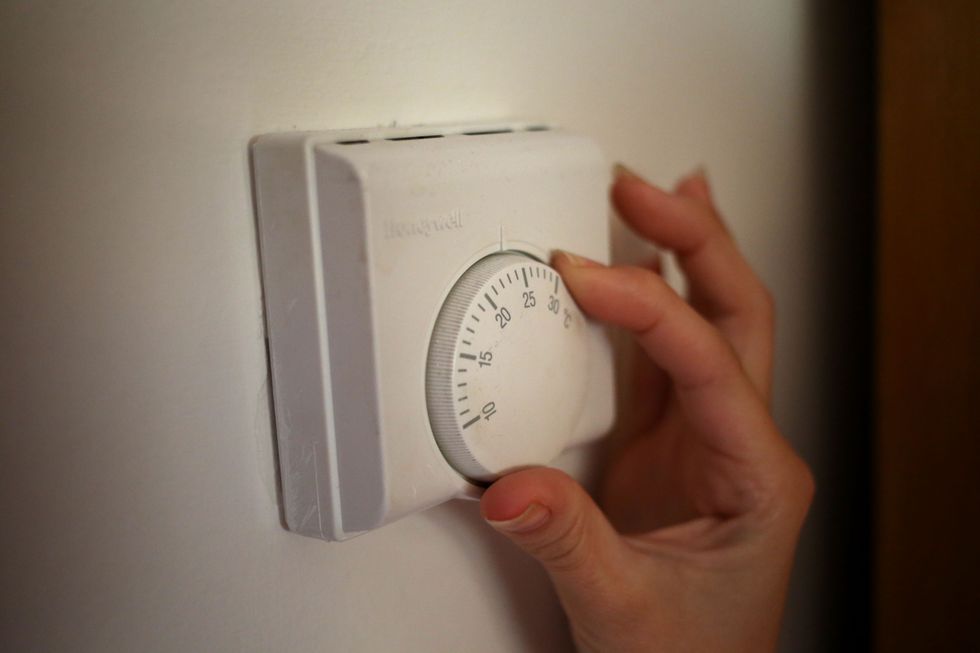 A person turns down a thermostat