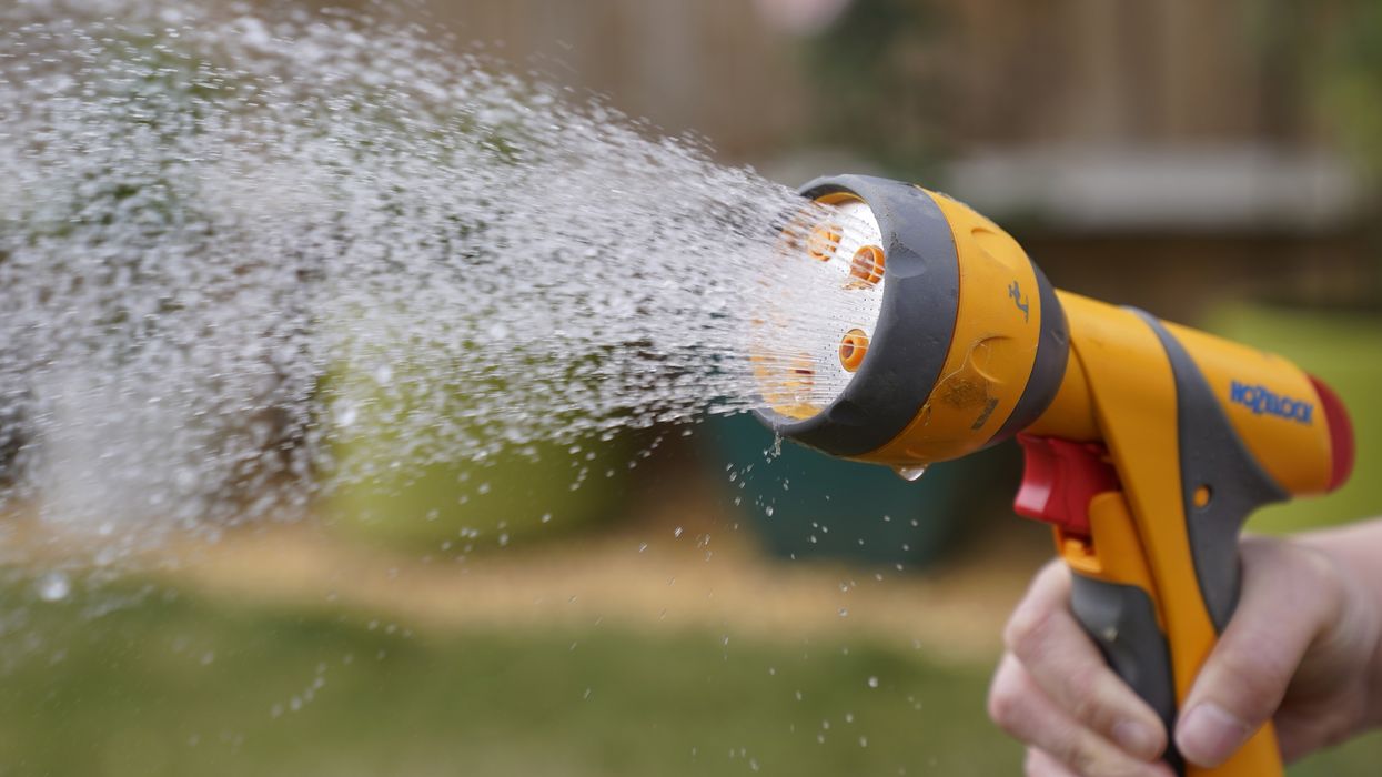 A person uses a hosepipe to water their lawn in Basingstole, Hampshire.