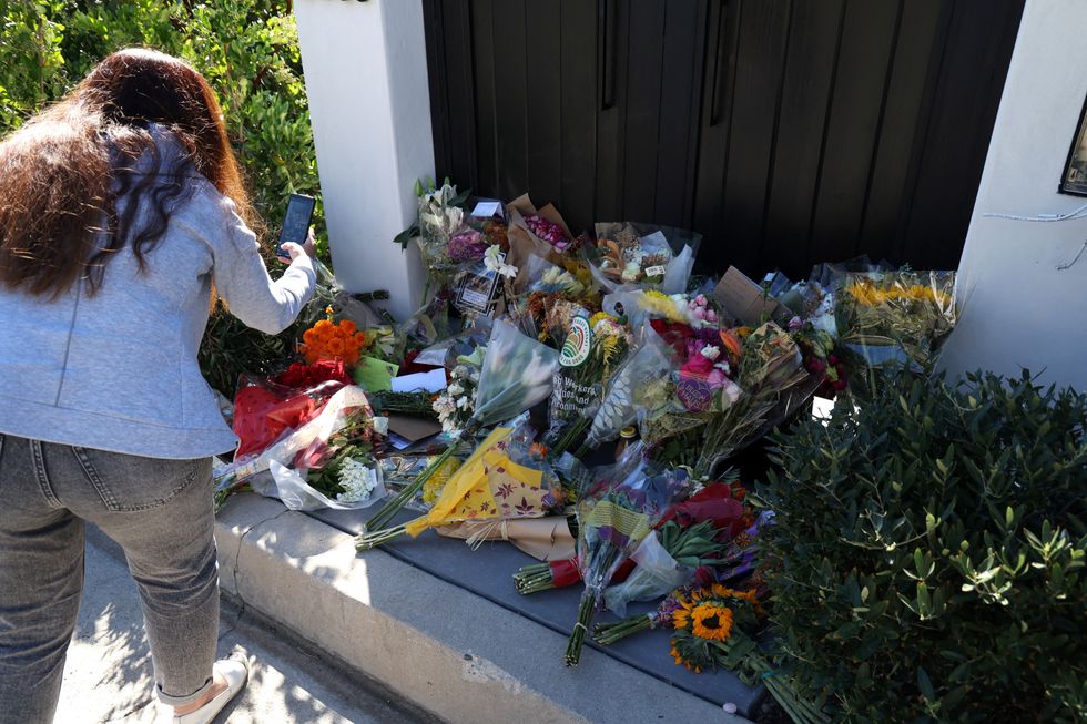 A person uses her mobile phone outside the home of late actor Matthew Perry