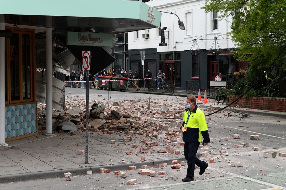 A person walks past damage to the exterior of a restaurant following an earthquake in the Windsor suburb of Melbourne, Australia.