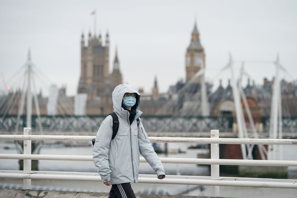 A person wearing a face mask crosses Waterloo Bridge, in London, as Plan B measures are lifted in England. Face coverings will no longer be mandatory in any setting, and the NHS Covid Pass will no longer be compulsory for entry into nightclubs and other large venues. Picture date: Thursday January 27, 2022.