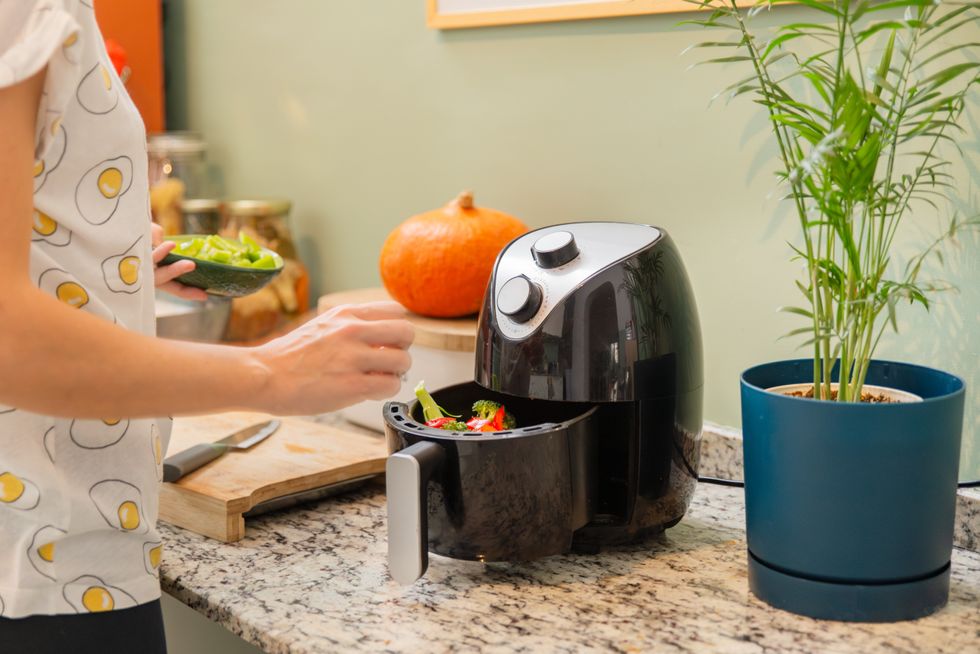 A photo of a woman using an air fryer
