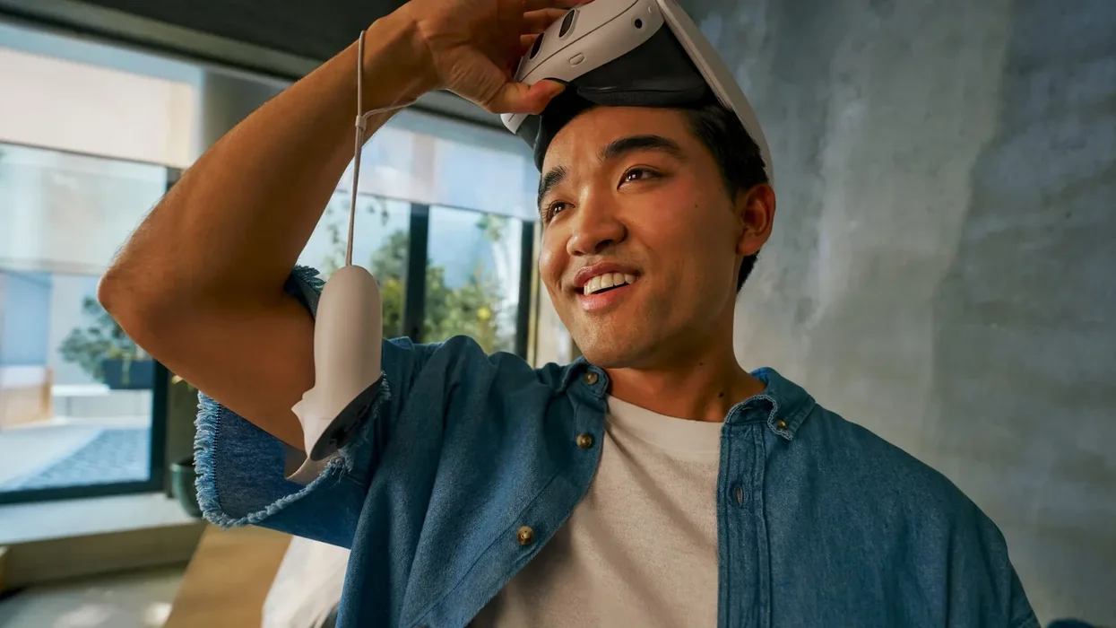 a picture of a man lifting up the meta quest 3 headset from his eyes with a controller dangling on his arm