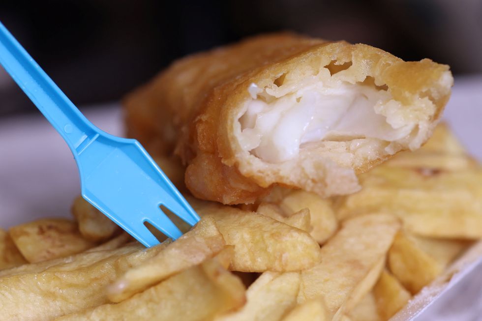 A plastic fork stands in a portion of fish and chips from a fish and chip shop is pictured in Manchester