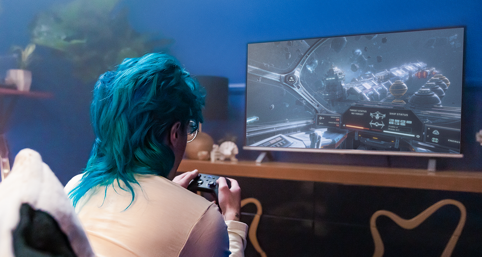 a player sits with a controller playing video games on their tv