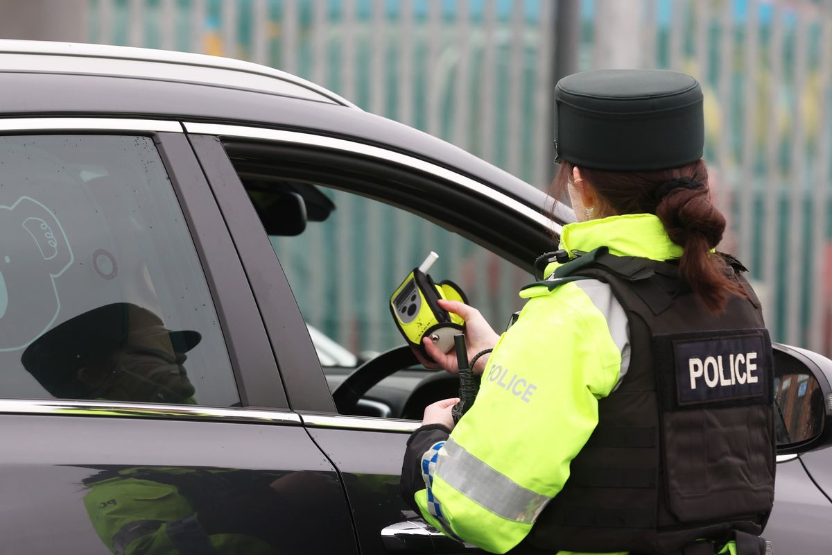A police officer conducting a roadside breathalyser test on a driver