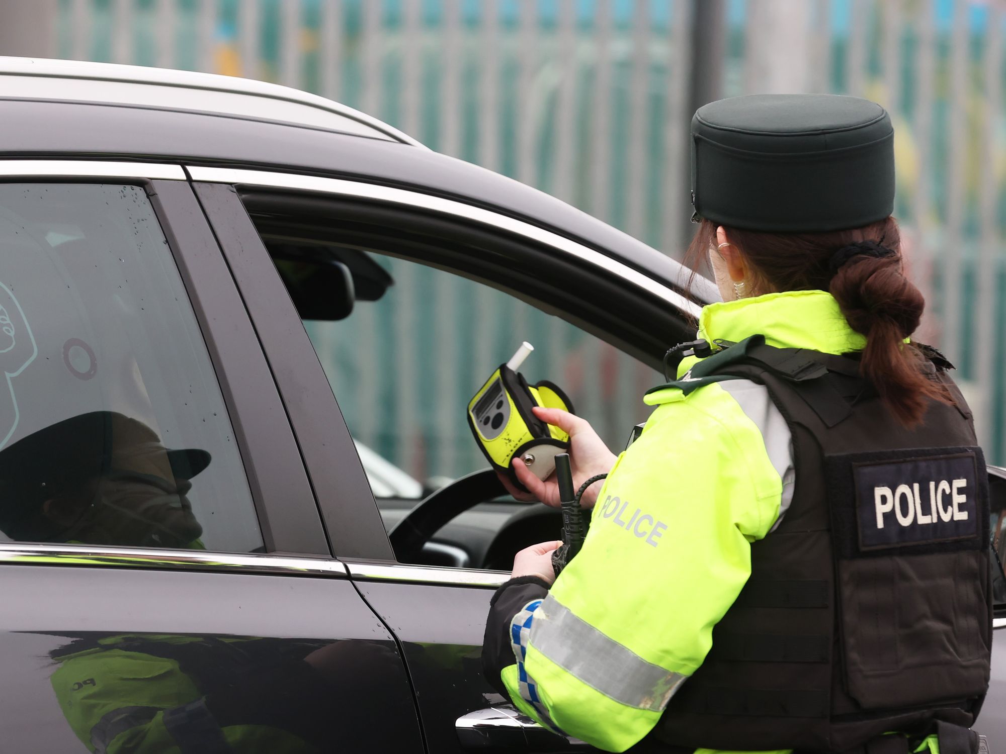 A police officer conducting a roadside breathalyser test on a driver