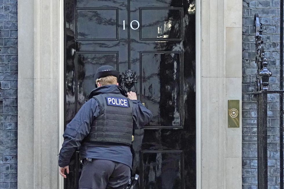 A police officer knocks on the door of the Prime Minister's official residence in Downing Street, Westminster, London, as public anger continues following the leak on Monday of an email from Boris Johnson's principal private secretary, Martin Reynolds, inviting 100 Downing Street staff to a %22bring your own booze%22 party in the garden behind No 10 during England's first lockdown on May 20, 2020. Picture date: Wednesday January 12, 2022.