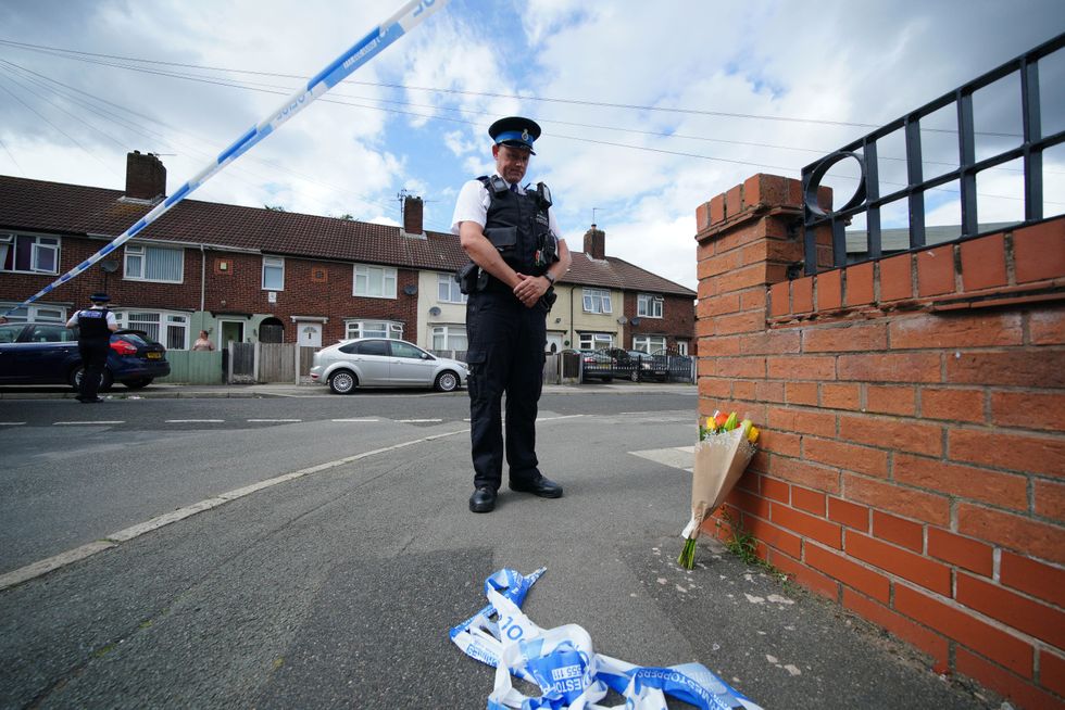 A police officer lays flowers near to the scene in Kingsheath Avenue, Knotty Ash, Liverpool, where a nine-year-old girl has been fatally shot. Officers from Merseyside Police have started a murder investigation after attending a house at 10pm Monday following reports that an unknown male had fired a gun inside the property. Picture date: Tuesday August 23, 2022.