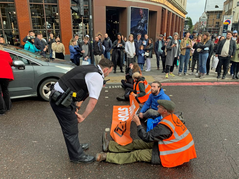 A police officer speaks to Just Stop Oil activists blocking the road on Commercial Street in east London. Issue date: Sunday October 30, 2022.