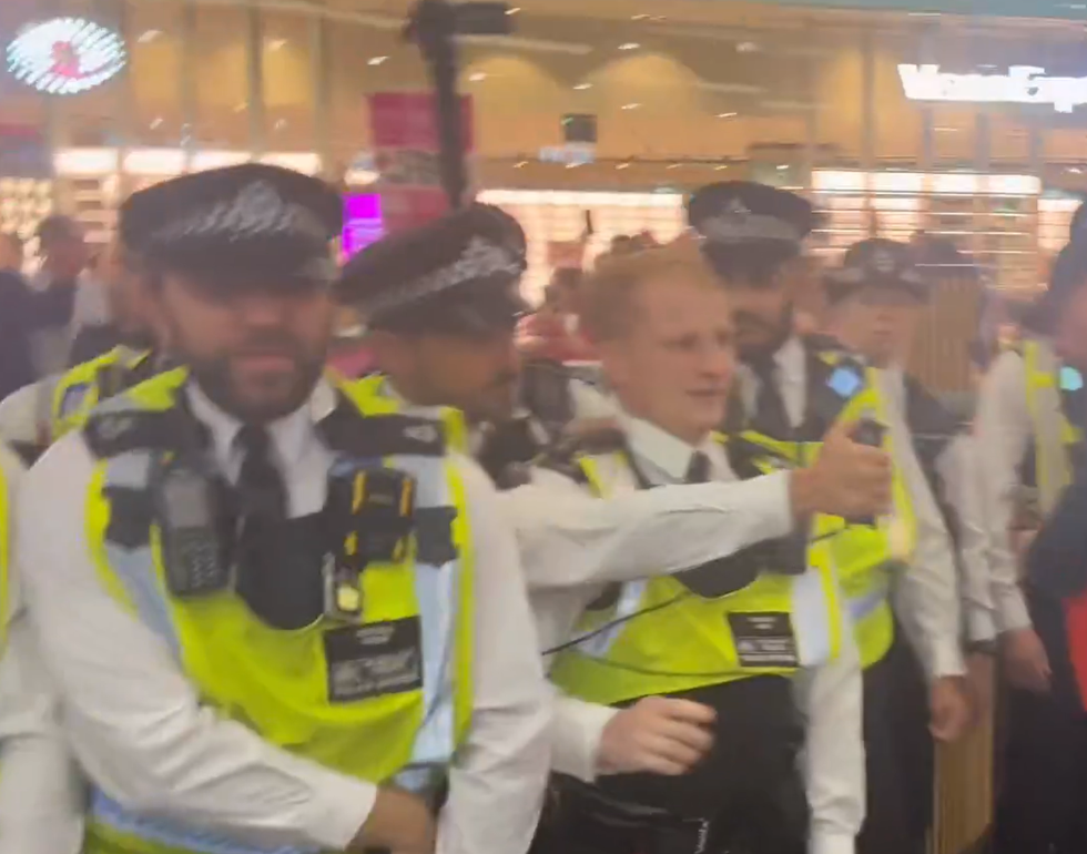 A police officer sprays PAVA spray at the Canary Wharf protest