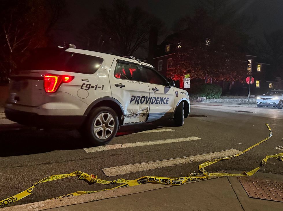 A police vehicle drives past police tape lying in the street after the shooting at Brown University in Providence, Rhode Island