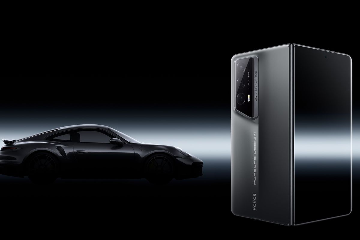 a porsche 911 is pictured in the background behind an honor magic v2 folding phone  