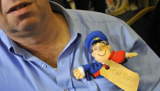 A postal worker has a Postman Pat sticking out of his top pocket as he takes part in a strike in London, in an escalating row over jobs, pay and services, threatening the worst disruption to mail deliveries for years.