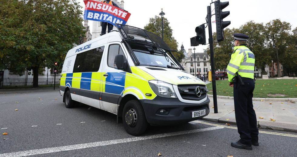 A protester from Insulate Britain stands on a police van as they block the road in Parliament Square, central London. Picture date: Thursday November 4, 2021.