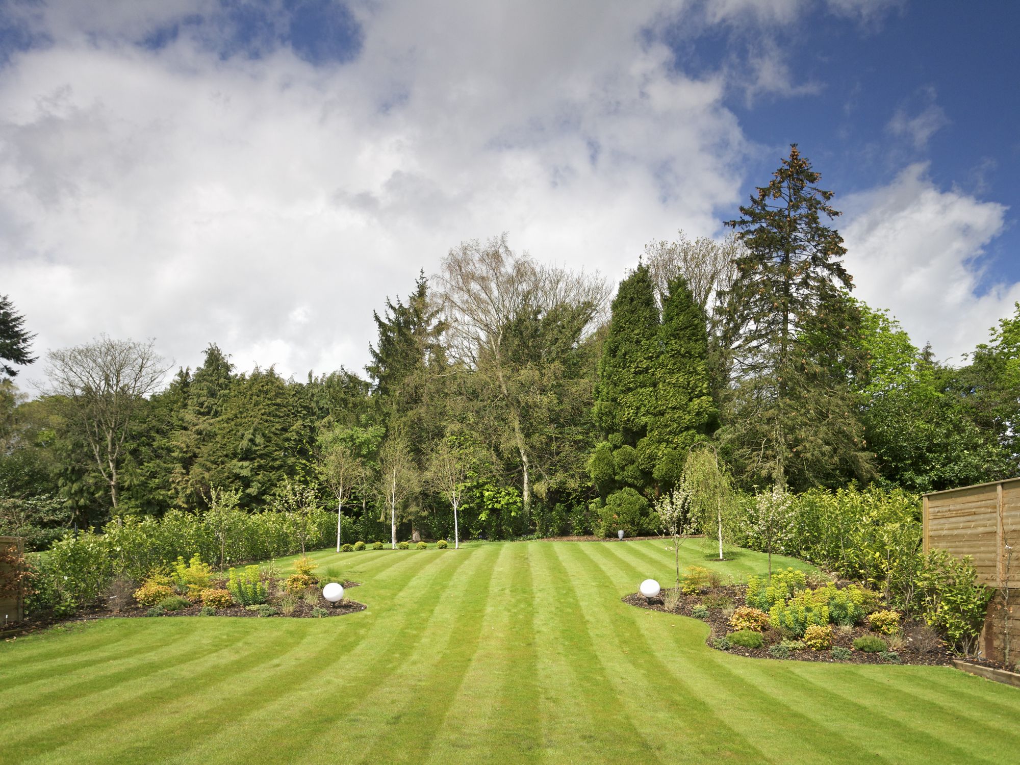 A recently mowed lawn, decorated with some flower beds