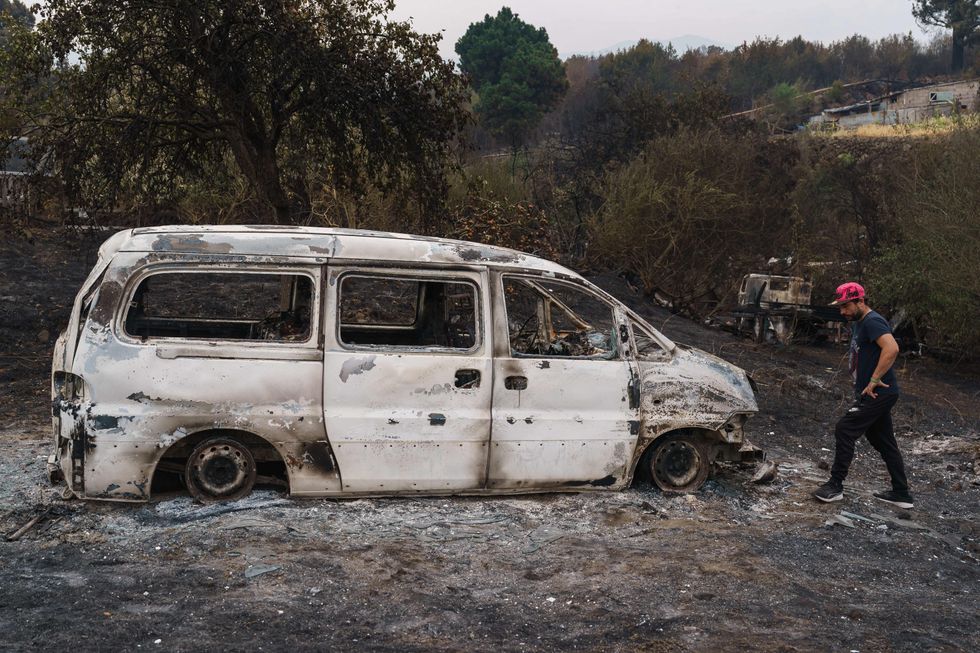 A resident looks at his charred car after returning to his home during the August wildfire
