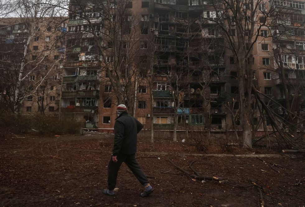 A resident walks near an apartment building damaged during a Russian drone strike, which happened late evening on Monday, amid Russia's attack on Ukraine
