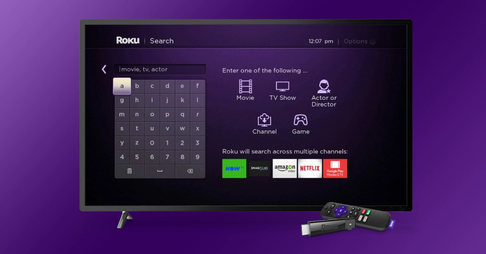 a roku stream stick and remote are pictured lying in front of a smart tv running the roku search menu