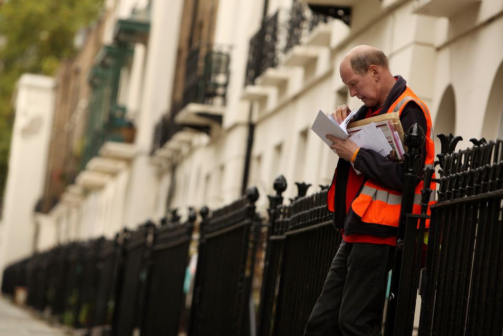 A Royal Mail postman delivers mail