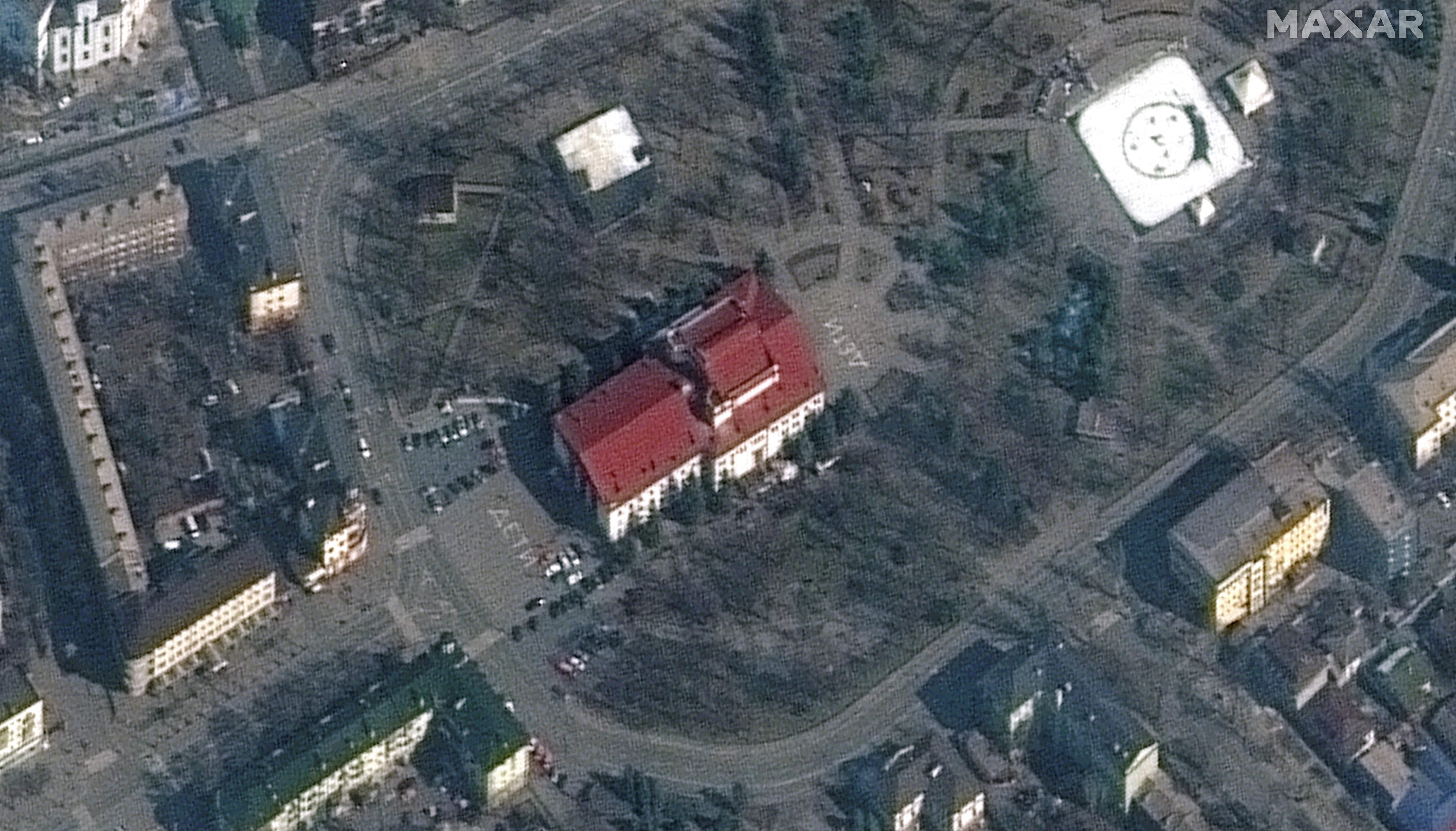 A satellite image shows a closer view of Mariupol Drama Theatre before bombing, as a word %22children%22 in Russian is written in large white letters on the pavement in front of and behind the building.