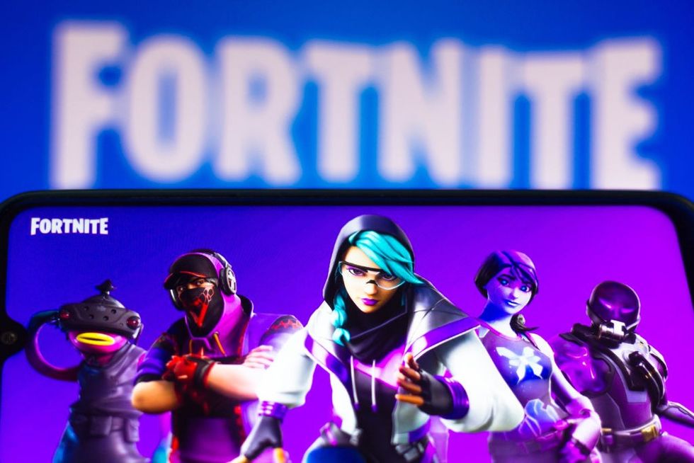 a screenshot of Fortnite pictured on a phone screen with the logo pictured behind