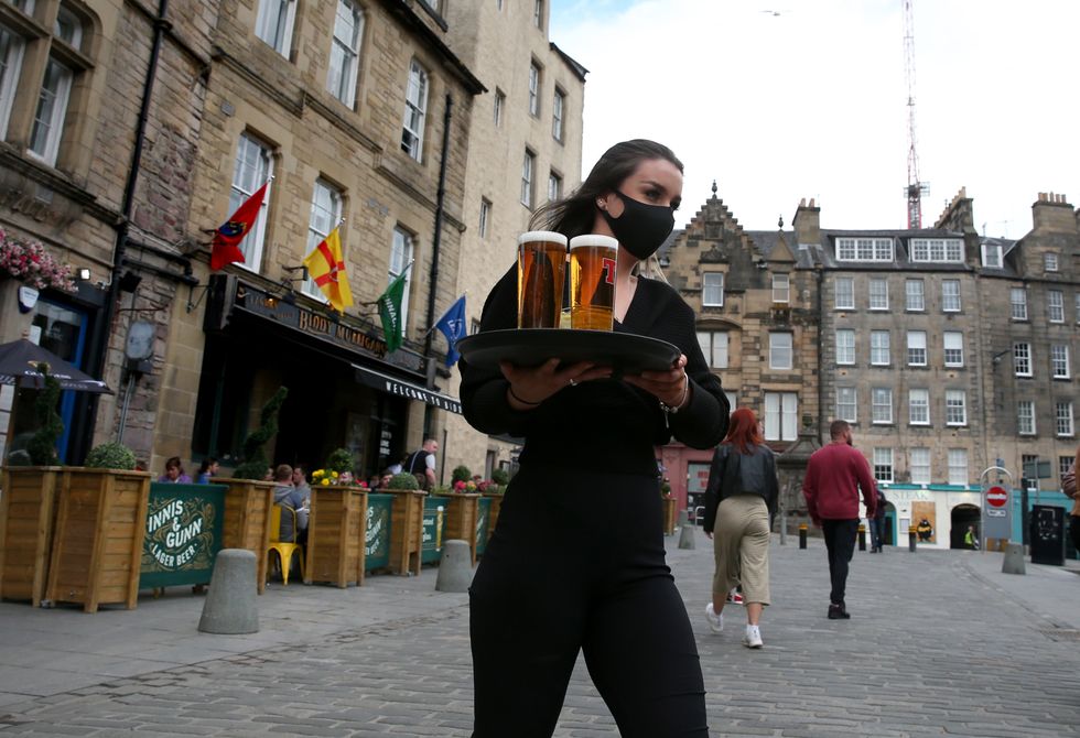 A server carries a tray of drinks from a pub in the Grassmarket in Edinburgh, as Scotland returns to table service in venues serving alcohol.